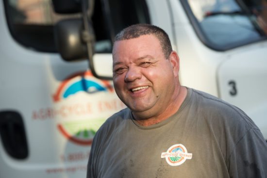 Agri-Cycle_Energy_Employee Picture of an Agri-Cycle Energy employee smiling infront of a ACE truck.