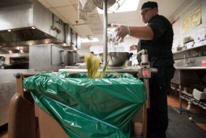 Chef discards food waste into Agri-Cycle tote in restaurant.